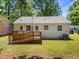 Cozy home featuring a wooden deck, green grass and partial shade from large trees at 1208 W Murray Ave, Durham, NC 27704