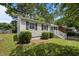 View of a charming single story home with lush landscaping, classic shutters, and a well-manicured lawn at 1208 W Murray Ave, Durham, NC 27704