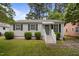Charming single-story home featuring a light blue front door, manicured landscaping, and classic black shutters at 1208 W Murray Ave, Durham, NC 27704