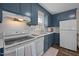 Charming kitchen with blue cabinets, white appliances, and tile backsplash offers a cozy and functional cooking space at 1208 W Murray Ave, Durham, NC 27704