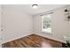 Bedroom with wood-look flooring, a window, and corner shelving with plants at 1220 Sherbrooke Ct, Raleigh, NC 27612