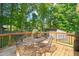 Enjoy outdoor dining on this wooden deck surrounded by lush green trees and a metal table with four chairs at 1220 Sherbrooke Ct, Raleigh, NC 27612