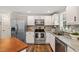 Bright kitchen features stainless steel appliances, granite counters, mosaic backsplash, and wood look flooring at 1220 Sherbrooke Ct, Raleigh, NC 27612