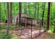 View of a shed and attached animal shelter with fenced area, nestled among mature trees at 135 Crooked Creek Run, Louisburg, NC 27549