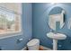 Powder room featuring a sleek pedestal sink, toilet, and window with natural light, designed with contemporary fixtures at 138 Tramway Cir, Angier, NC 27501