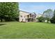 Spacious backyard featuring a lush green lawn, mature trees, and a screened-in porch, perfect for outdoor enjoyment at 1612 Rainesview Ln, Apex, NC 27502