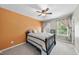 Bright bedroom with a bold orange accent wall, large window, and ceiling fan at 1612 Rainesview Ln, Apex, NC 27502