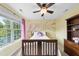 Well-lit bedroom with yellow walls, light carpeting, ceiling fan, and a picturesque view from the window at 1612 Rainesview Ln, Apex, NC 27502