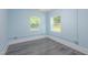Light blue bedroom featuring 2 windows and gray wood-look flooring at 1917 Tucker St, Burlington, NC 27215