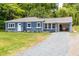 Charming blue brick home with a manicured lawn, covered parking, and gravel driveway at 1917 Tucker St, Burlington, NC 27215