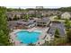 Aerial view of the community pool with lounge chairs, red umbrellas, clubhouse, and parking in a neighborhood at 2135 Vittorio Ln, Apex, NC 27502