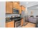 Well-equipped kitchen with stainless appliances, wood cabinetry, and a view of the living space at 2242 Sweet Annie Way, Wake Forest, NC 27587