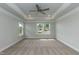 Bright bedroom featuring a ceiling fan, tray ceiling, neutral carpet, and natural light from the windows at 279 Hopewell Branch Ct, Smithfield, NC 27577