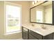 Bathroom featuring a double vanity with modern faucets, a framed mirror, and natural light from a window at 3002 Dog Rose Dr # 310, Durham, NC 27703