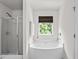 Bathroom showcasing white tub and shower with modern fixtures and natural light from a window at 3169 Diana Cir, Burlington, NC 27215