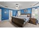 Cozy bedroom featuring blue accent wall, ceiling fan, and ample natural light from large windows at 3169 Diana Cir, Burlington, NC 27215