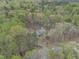 Aerial view showcases a blue house nestled among trees, with a playground and car visible at 3418 Carriage Trl, Hillsborough, NC 27278