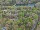Aerial view highlights a property near a lake, featuring mature trees and meandering roads through a wooded landscape at 3418 Carriage Trl, Hillsborough, NC 27278
