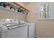 Functional laundry room with modern washer and dryer, storage shelves and natural light at 3418 Carriage Trl, Hillsborough, NC 27278
