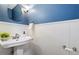 Cozy powder room with a white pedestal sink, framed mirror, and beautiful blue accent wall at 3418 Carriage Trl, Hillsborough, NC 27278