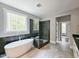 Bright bathroom features soaking tub, walk-in shower, and views of wooded property at 35 Big Bear Dr, Pittsboro, NC 27312