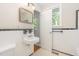 White tiled bathroom with black accent trim, sink, and view of window at 421 Ridgefield Rd Rd, Chapel Hill, NC 27517