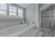Bathtub with tile surround, next to a glass shower and windows for natural light at 4562 Brighton Ridge Dr, Apex, NC 27539