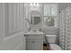 Well-lit half bathroom with white fixtures, a round mirror, and a decorative shower curtain at 4562 Brighton Ridge Dr, Apex, NC 27539