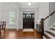 Elegant foyer with hardwood floors, staircase, dark wood door, and natural light from a nearby window at 4562 Brighton Ridge Dr, Apex, NC 27539