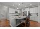 Bright kitchen features stainless appliances, white cabinets, granite counters, and a kitchen island with seating at 4562 Brighton Ridge Dr, Apex, NC 27539