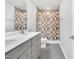 Modern bathroom featuring double vanity, grey tile floor, and shower-tub combination with colorful shower curtain at 4601 Okeechobee Ct, Fuquay Varina, NC 27526