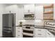 A modern kitchen with stainless steel appliances, black countertops, and white cabinets is featured at 5180 Old Powell Rd, Holly Springs, NC 27540