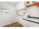 Well-lit laundry room with natural light, sink, cabinets, and storage racks for organization at 5180 Old Powell Rd, Holly Springs, NC 27540