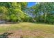Lush green backyard featuring mature trees, offering a private and serene outdoor space at 701 Veterans Dr, Elon, NC 27244