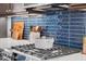 Close up of kitchen with stainless steel gas range, dark cabinets, white counters, and blue tile backsplash at 805 Hyperion Aly, Wake Forest, NC 27587