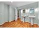 Light-filled bathroom featuring double pedestal sinks, hardwood floors, and built-in linen storage at 823 Churchill Dr, Chapel Hill, NC 27517