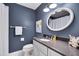 Stylish bathroom featuring a vanity, round mirror, and modern fixtures against a dark wall at 823 Churchill Dr, Chapel Hill, NC 27517