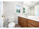 Bathroom features a wooden vanity, toilet, vinyl floors, and a well-lit mirror at 84 Sycamore Lake Rd, Siler City, NC 27344