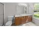 Bright bathroom features double sinks, wood vanity, and adjacent toilet at 909 Alderleaf Dr, Fuquay Varina, NC 27526