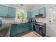 Updated kitchen features turquoise cabinetry, stainless appliances, hardwood floors, and a window for natural light at 909 Alderleaf Dr, Fuquay Varina, NC 27526