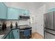 Well-lit kitchen features stainless steel appliances, turquoise cabinetry, and white tile backsplash at 909 Alderleaf Dr, Fuquay Varina, NC 27526