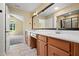 Bathroom features double sink vanity with wood cabinets, large mirror, and tiled flooring at 924 Carolina Bell Rd, Apex, NC 27502