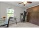 Bright bedroom with a ceiling fan, a large window, and a closet. Featuring a treadmill and glass desk at 1574 Dorsett Ln, Creedmoor, NC 27522