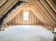 Unfinished attic space with exposed wooden beams and natural light from a window at 188 Buckaroo Dr, Louisburg, NC 27549