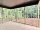 Covered back porch with wood flooring and railings overlooking a wooded backyard at 188 Buckaroo Dr, Louisburg, NC 27549