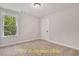 Neutral bedroom featuring carpeted floors, bright natural light from the window, and a white door at 188 Buckaroo Dr, Louisburg, NC 27549