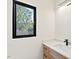 Bathroom sink with a wooden cabinet, white countertop, black faucet and a modern light fixture at 2205 Tampa Ave, Durham, NC 27705