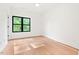 Bright bedroom features hardwood floors, a ceiling light, and a large window with green leafy views at 2205 Tampa Ave, Durham, NC 27705