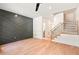 Spacious living room featuring hardwood floors, a modern accent wall, staircase, and abundant natural light at 2205 Tampa Ave, Durham, NC 27705