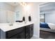 Double sink bathroom with a black vanity, a bright mirror, and a door to the bedroom at 3413 S Beaver Ln, Raleigh, NC 27604